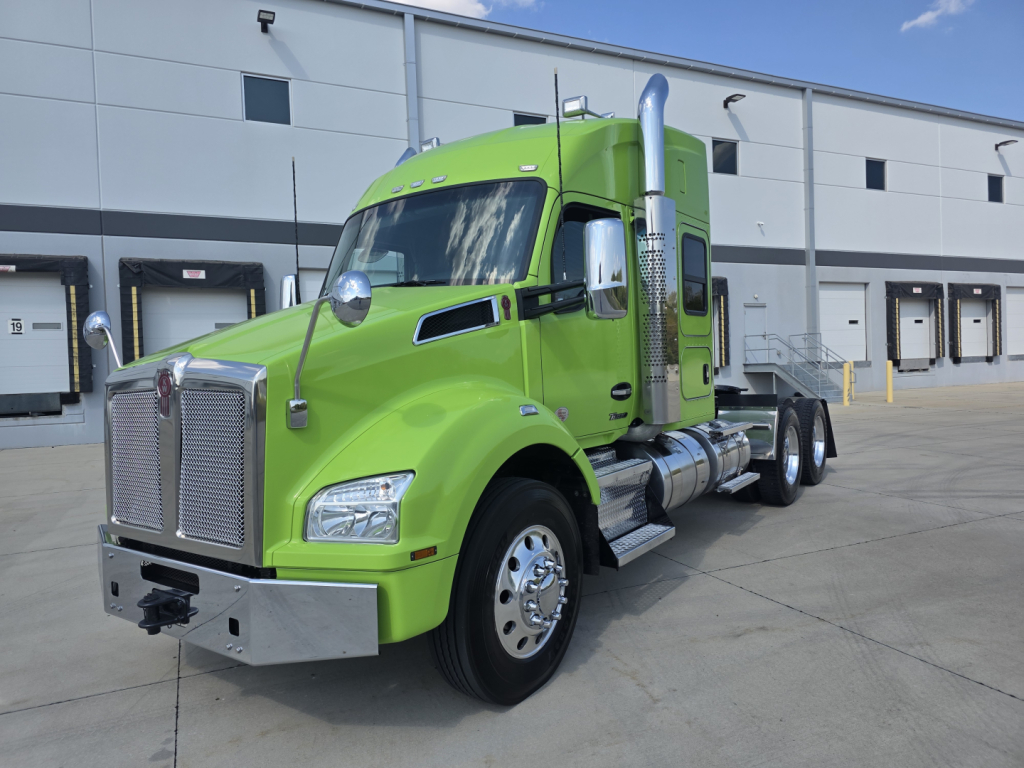 Kenworth T880 row crop showing bright green sleeper cab with chrome exhaust stacks and front grille, side fuel tanks, and dual rear axles.