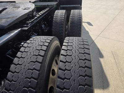 Kenworth T880 truck rear wheels and chassis view showing dual rear axles and heavy-duty tire tread.