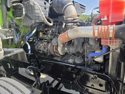 Kenworth T880 engine bay showing large intake hose, turbocharger, wiring, and coolant reservoir.