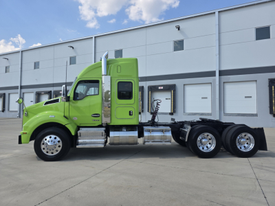 Green 2022 Kenworth T880 tractor side view showing cab, fuel tanks, rear axles, and wheel rims; no visible text on side other than door and cab features.