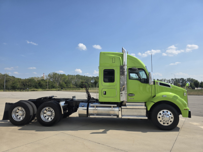 Kenworth T880 cargo tractor side view showing bright lime green sleeper cab and chassis with chrome fuel tanks and dual rear axles.