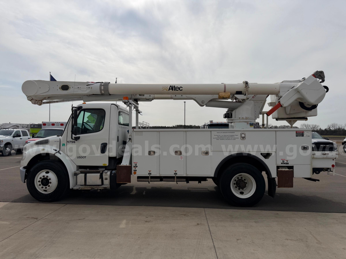 Altec AM55 bucket truck on Freightliner chassis side view showing bucket control area and boom arm with stabilizers.