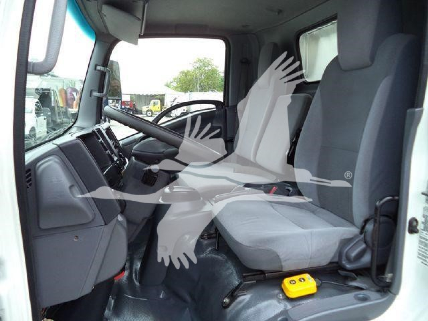 Isuzu NPR-HD cab interior view showing driver and front passenger seats, steering wheel, dashboard, and center console.