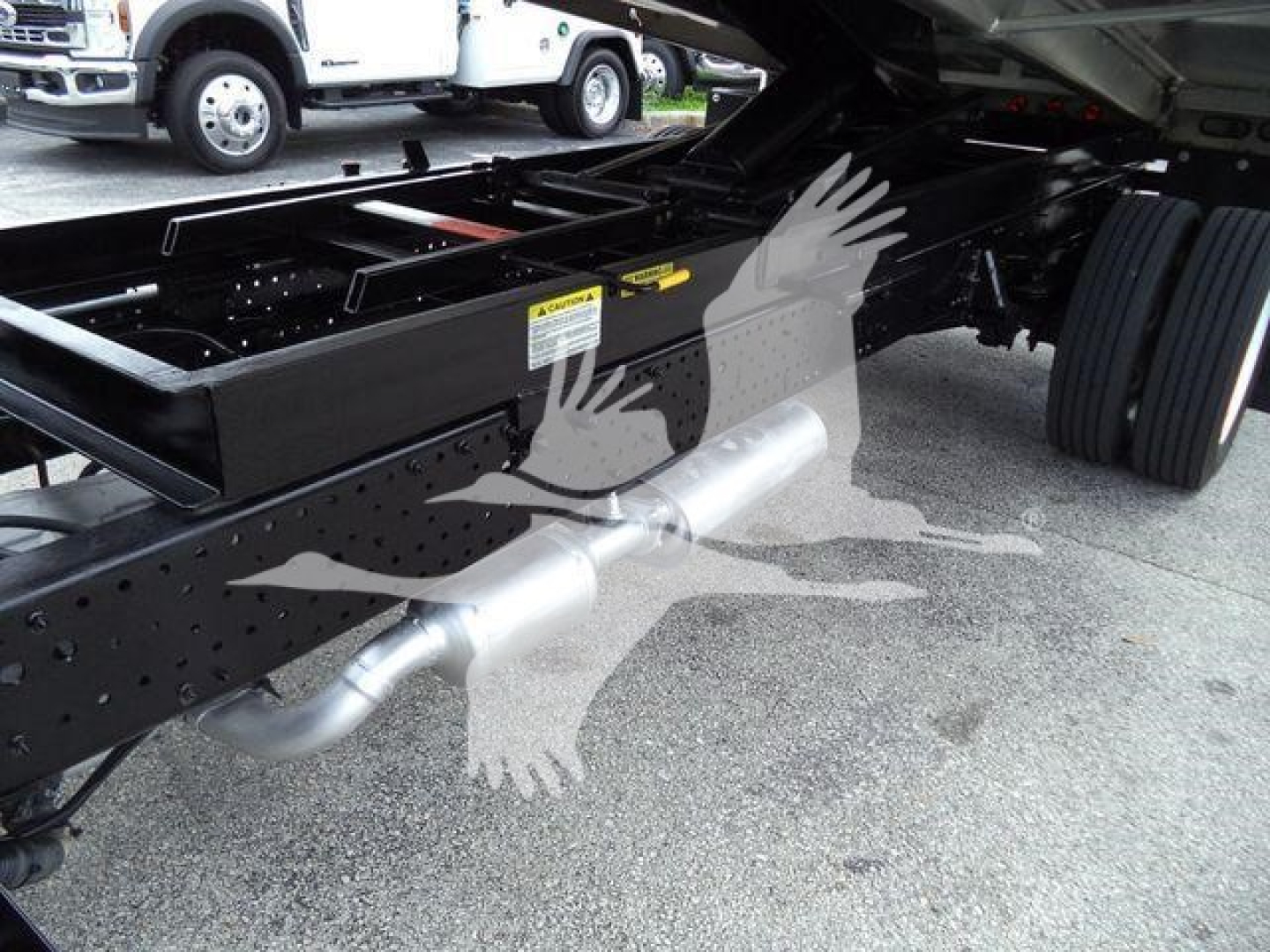 Isuzu NPR-HD truck chassis side view showing exhaust pipe and undercarriage with frame rails and dual rear wheels.