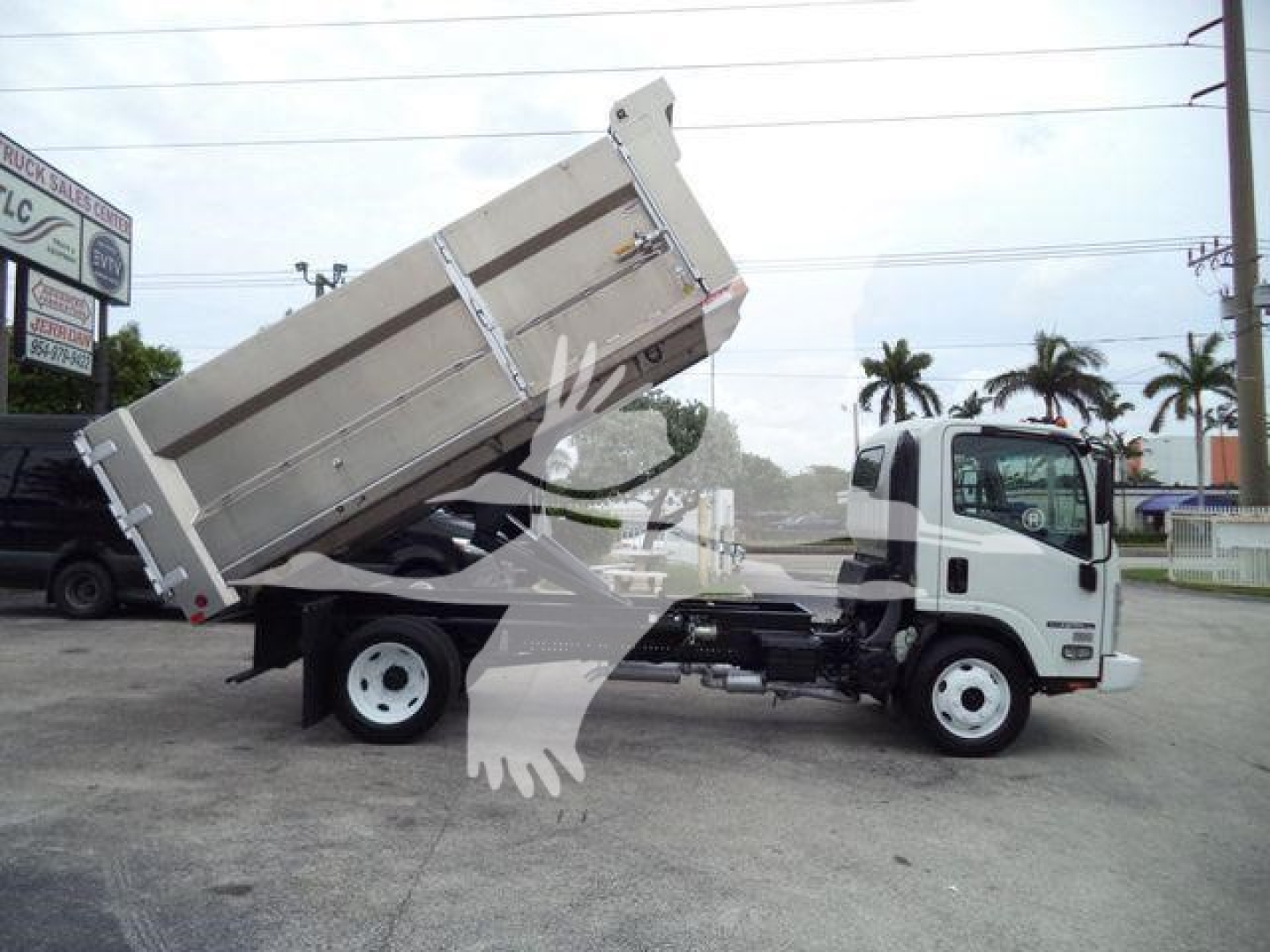 Isuzu NPR HD dump truck in profile with cargo bed raised showing hydraulic dump mechanism and side rails.