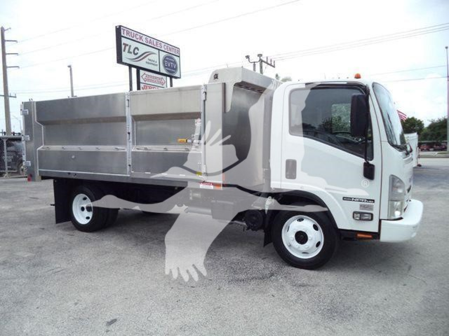 Isuzu NPR-HD truck with a silver dump bed and white cab in a dealership lot.