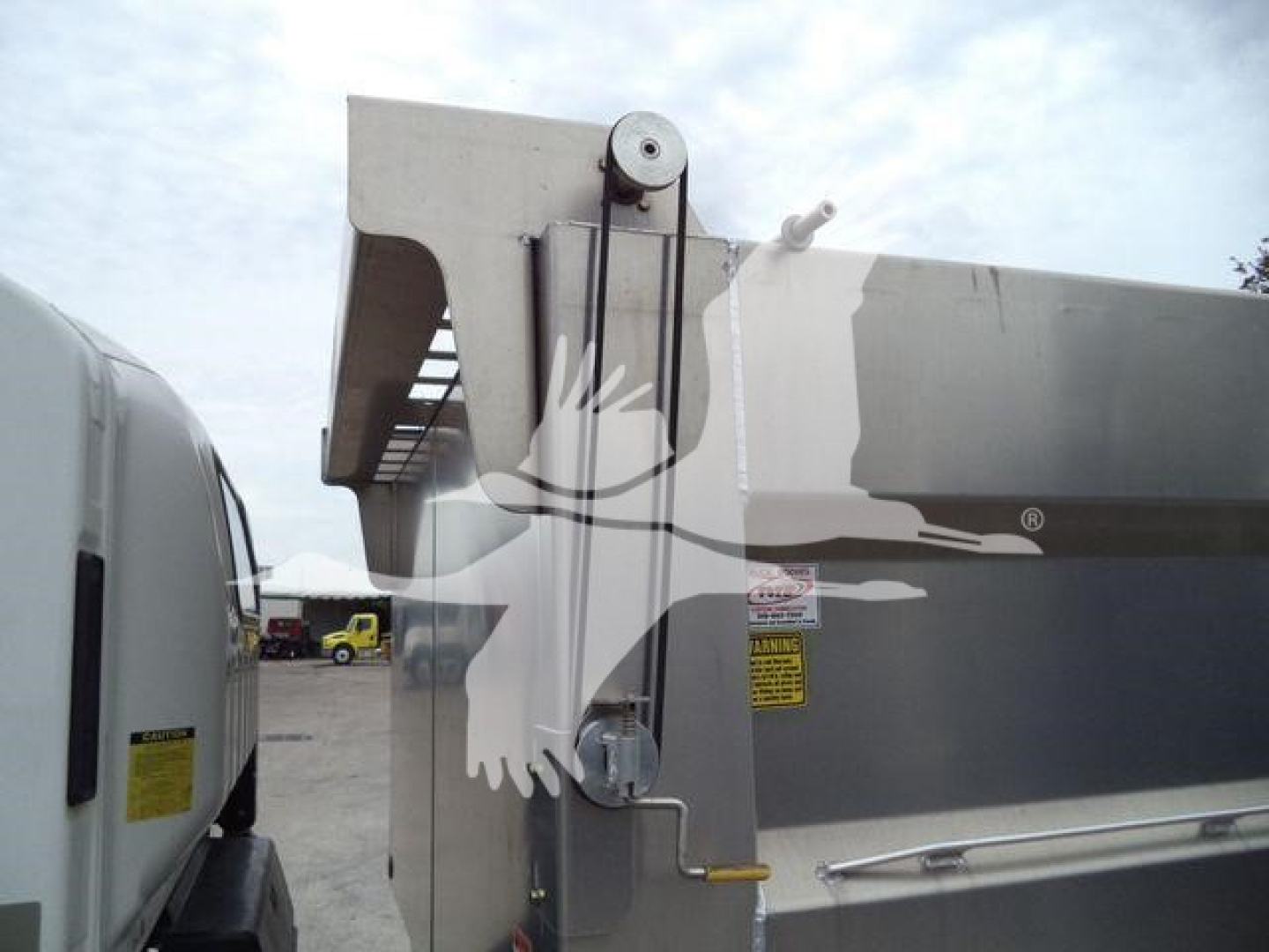 Isuzu NPR HD truck bed side with hoist mechanism and pulley, visible labels on side panel.