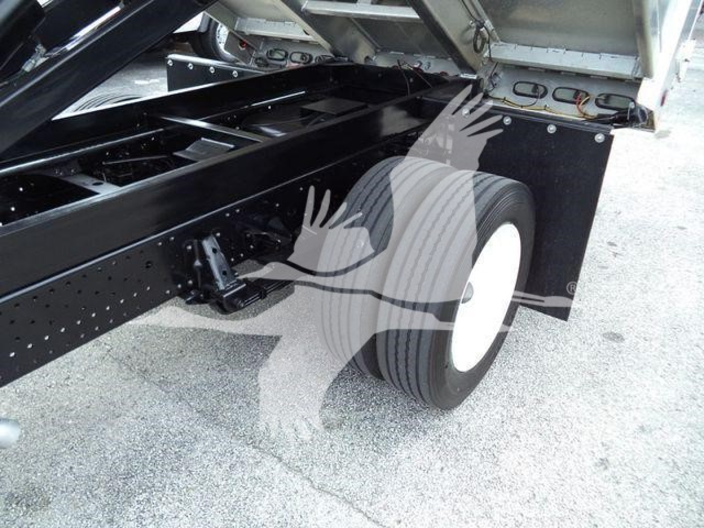 Isuzu NPR HD truck chassis showing rear dual wheels and raised bed with hydraulic components.
