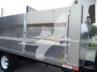 Isuzu NPR-HD dump truck side view showing large steel cargo body with rear double doors and warning stickers.