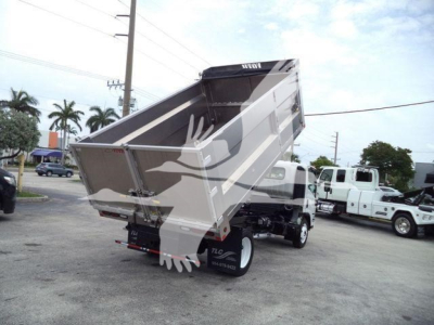 Isuzu NPR HD dump truck with raised metallic dump bed in a dealership lot. Visible text on sides includes Isuzu branding and numbers on wheel well.