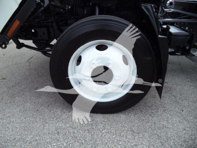 Isuzu NPR-HD truck front wheel showing a white steel wheel and tire, undercarriage components visible.