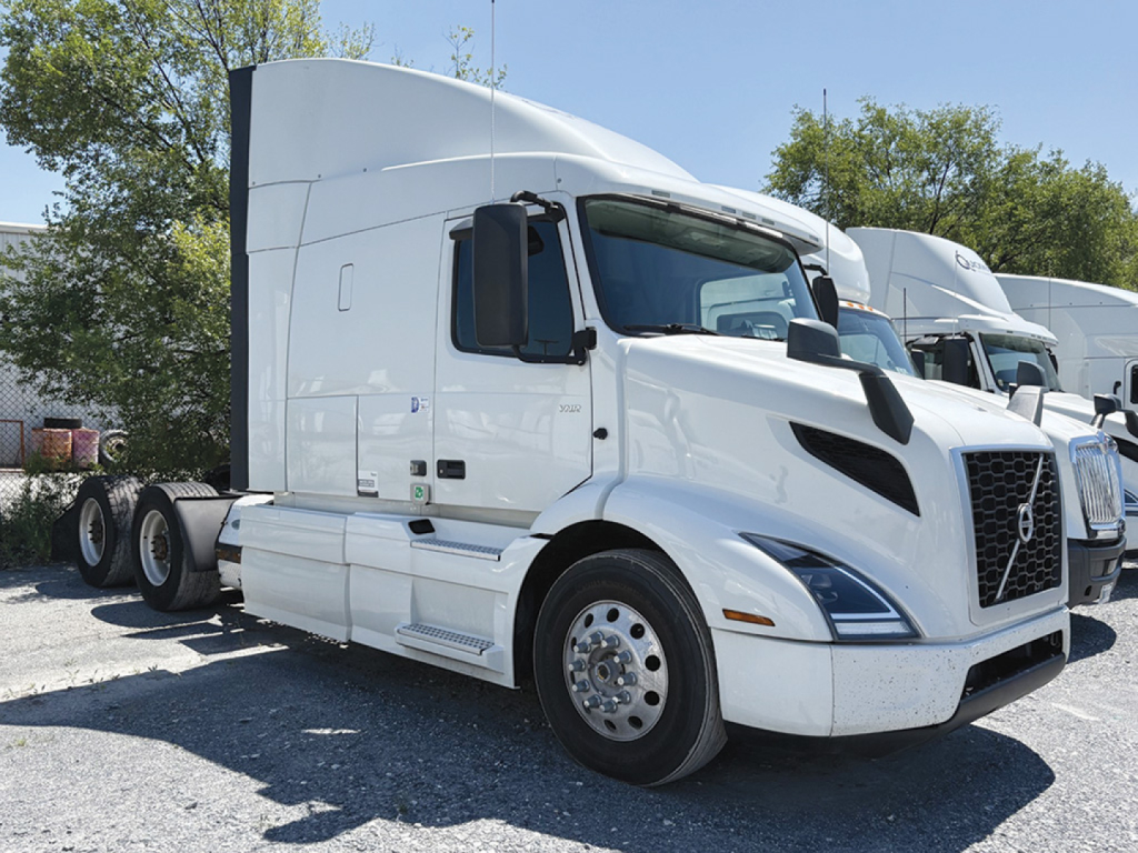 Volvo VNR 640 sleeper cab tractor in white with black grille and large sleeper, side view showing front wheels and cargo area.