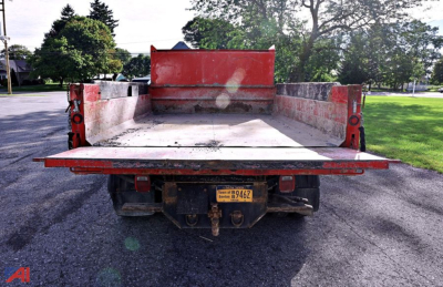 Truck bed of a 2019 Ford F-550 dump truck showing an empty flatbed with red sides and rear license plate area.