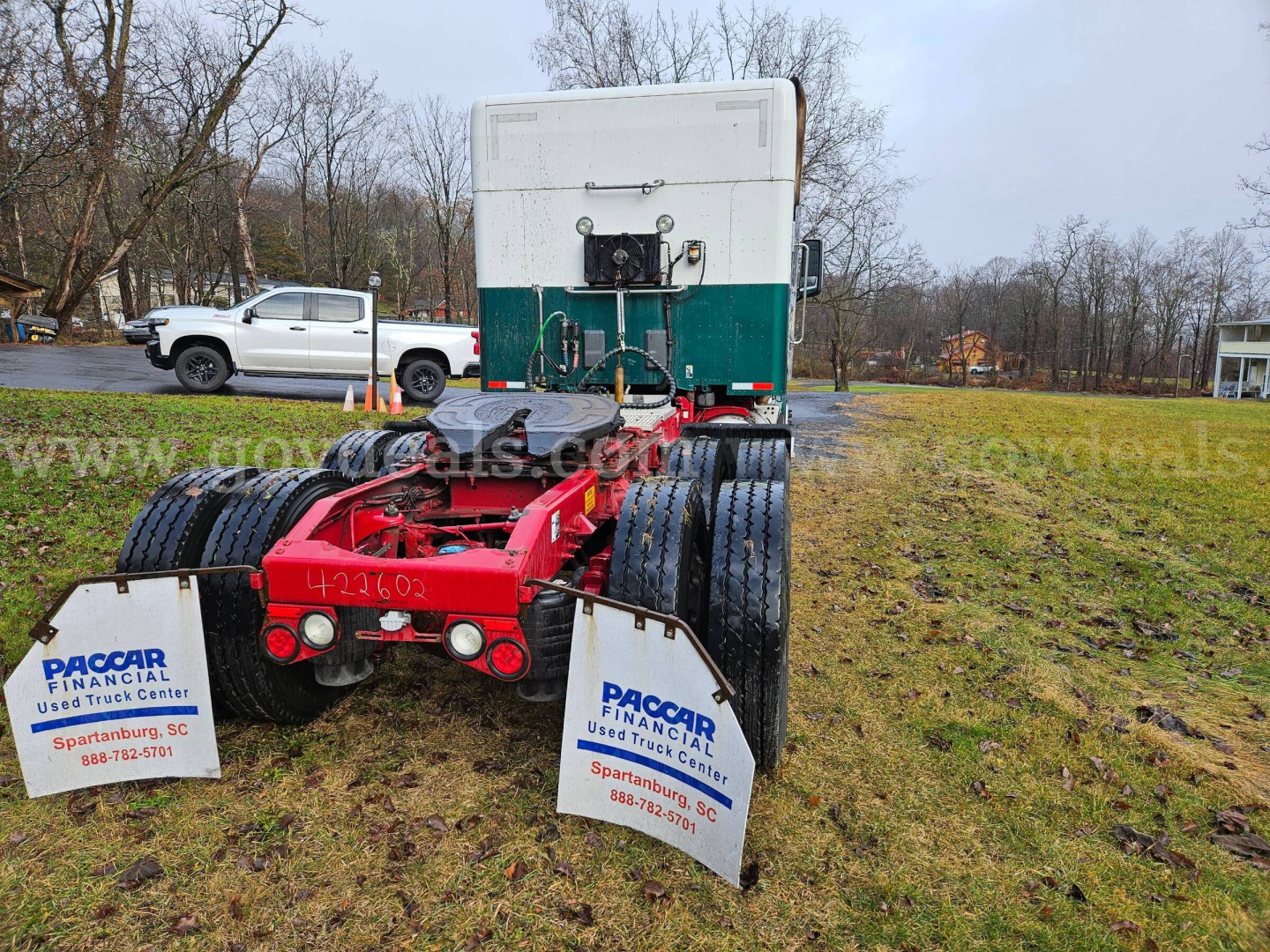 Truck tractor fifth wheel area showing red chassis and dual rear axles with white Paccar Financial signs on mudflaps.