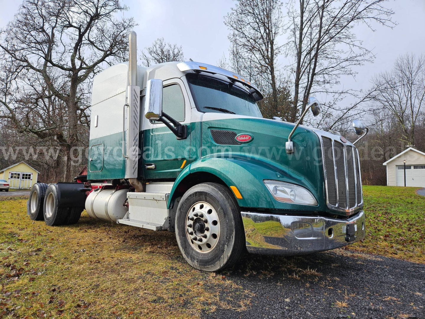Peterbilt 579 truck in teal with chrome bumper and stacked exhaust, side view showing cab and front wheel, used condition.