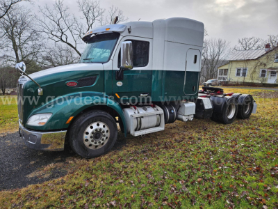 Peterbilt 579 tractor cab in green with gray sleeper, side view showing front wheel and hitch area, used vehicle