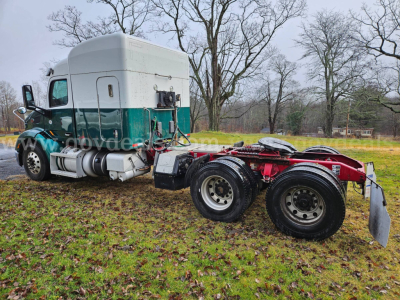 Peterbilt semi truck tractor with sleeper cab and rear dual axle chassis showing green and white cab and red chassis frame.