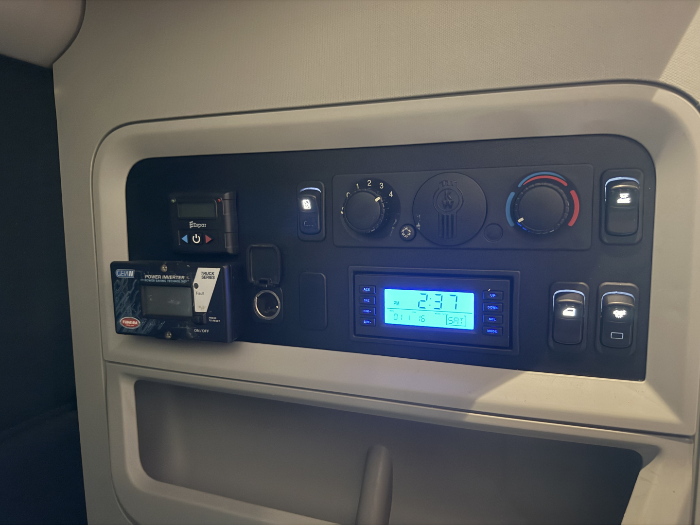 Kenworth T680 truck cockpit dashboard with gauges and blue digital display showing 2:37, control switches and USB socket