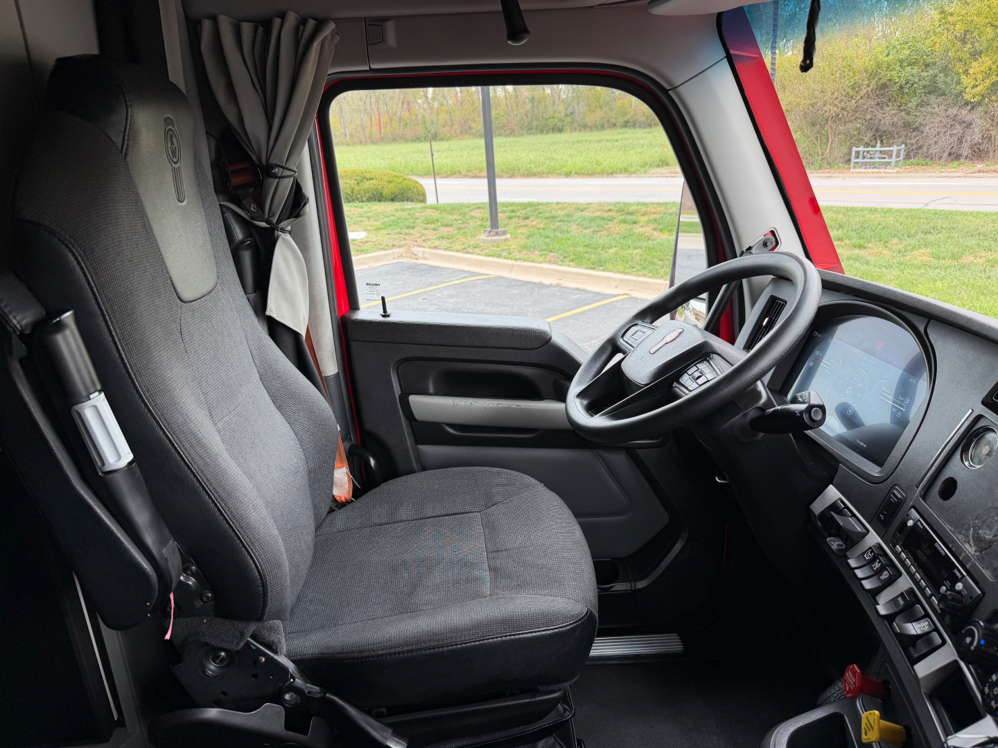 Kenworth T680 truck interior cab view showing steering wheel, driver seat, and dashboard with controls.