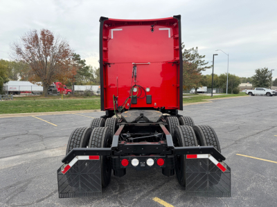 Kenworth T680 rear view showing chassis and dual rear axles with red sleeper cab and black mud flaps