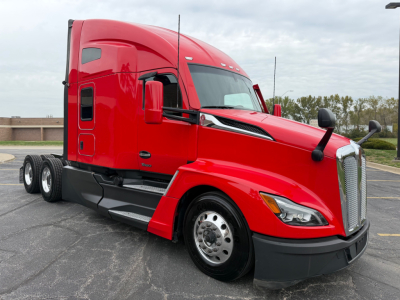 Kenworth T680 tractor unit in red, side view showing aerodynamic hood, dual rear axles, and chrome grille.