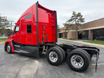 Red Kenworth T680 truck cab with sleeper, side view showing chassis and dual rear axles. Visible text includes VIN label area and Kenworth badge on cab.