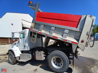 Dump truck bed raised showing Peterbilt 335 dump truck in service with white cab and red dump box.