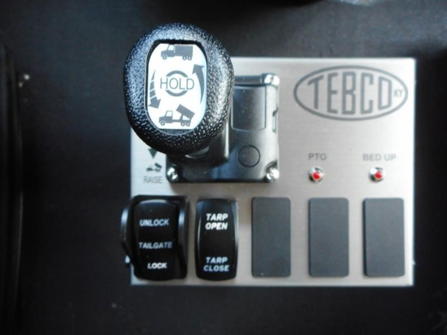 TEBCO control panel with hold icon on lever and four blank panels on metal plate.