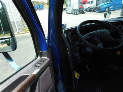Vehicle cab interior of a blue Western Star 47X truck showing steering wheel and driver's door area.