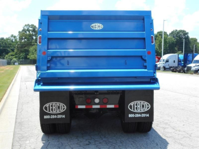 Dump truck bed rear view showing TEBCO bumper and mud flaps with TEBCO logos and phone numbers, blue cargo bed, license plate area blank.