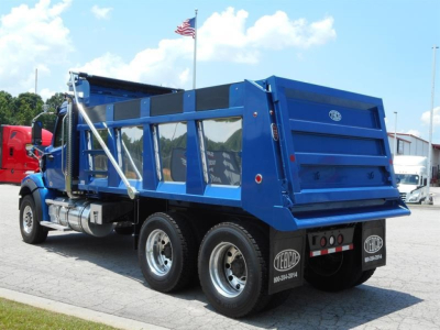 Dump truck rear and side view showing blue dump body, dual rear axles, and chrome fuel tanks under cab.