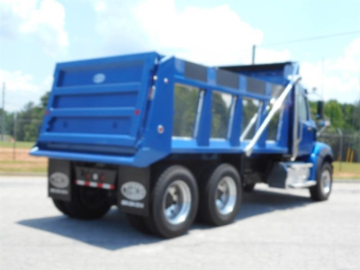 Blue Western Star dump truck with multiple rear axles and dump bed, side view showing dual tires and raised tailgate.