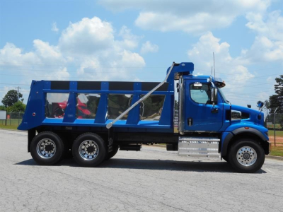 Blue Western Star 47X dump truck side view showing dump body with glass side panels and dual rear axles.