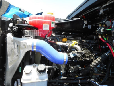 Western Star 47X engine bay showing blue coolant hose, red coolant reservoir, black plastic ducting, and various hoses and metal components.