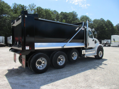 Western Star 49X dump truck side view showing black dump body with side rails, dual rear axles, chrome wheels, and white cab with chrome exhaust stacks.