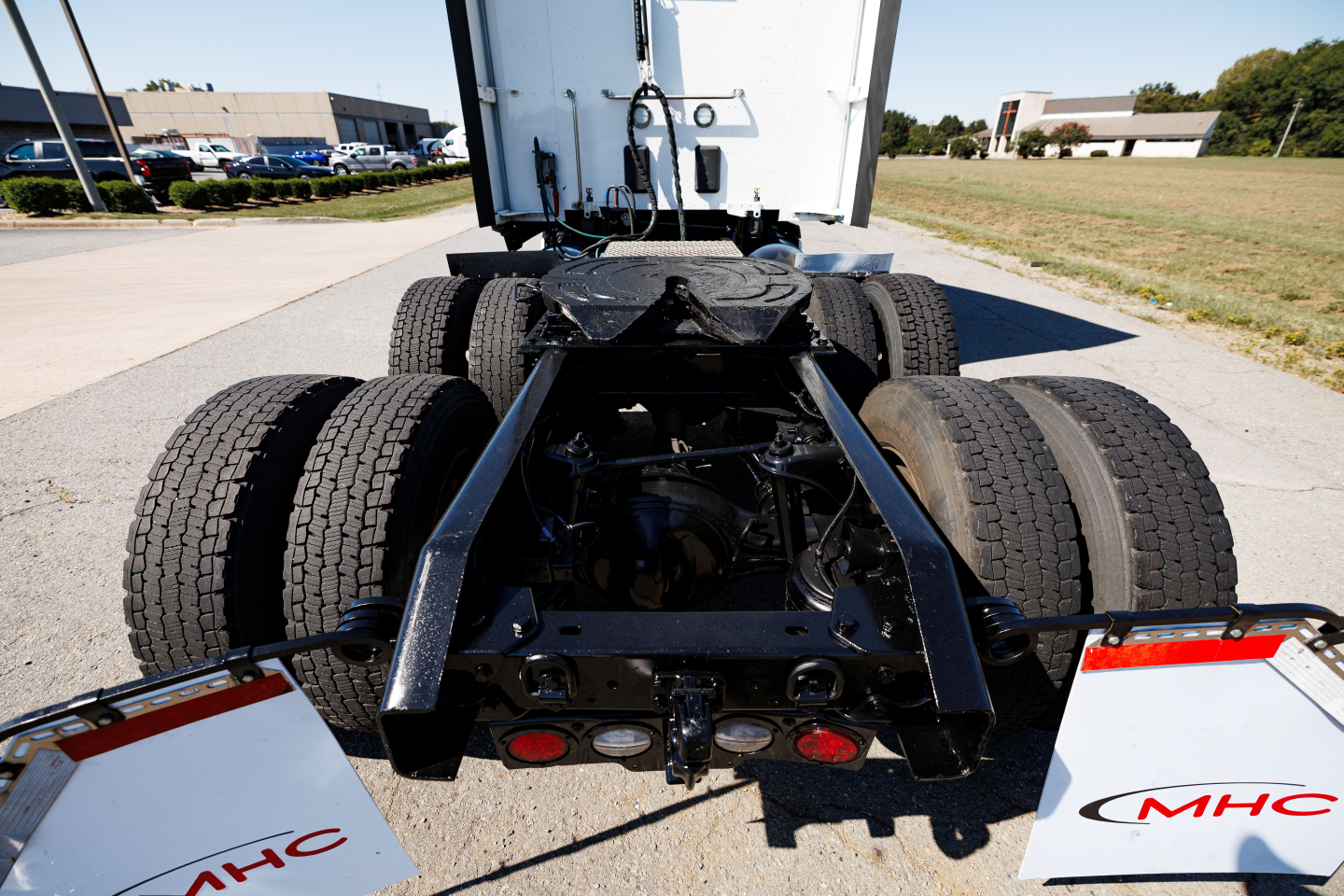 Truck rear view showing fifth-wheel and dual rear axles of a Kenworth T680 with black chassis and attached mud flaps.
