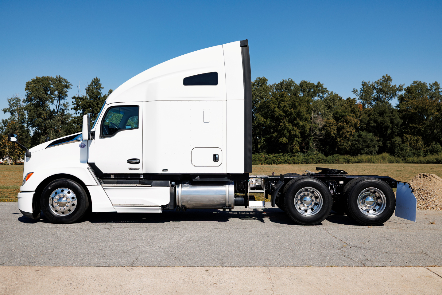 Kenworth T680 sleeper cab tractor truck side profile showing white exterior and chrome wheels.