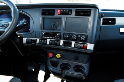 Kenworth T680 dash/center console view showing dashboard with climate controls, radio, cup holders, and storage compartments.