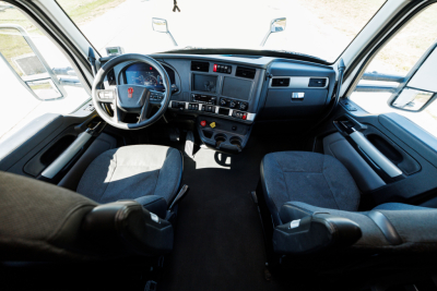 Kenworth T680 truck interior cabin view showing driver and passenger seats, dashboard with steering wheel, control panels, and center console.