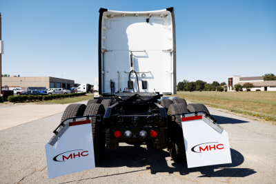 Kenworth T680 rear view showing chassis and mud flaps with MHC logos, fifth wheel area, and rear tires.