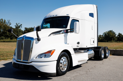 Kenworth T680 conventional sleeper tractor in white, front left angle, chrome grille, dual rear axles, badge details on hood