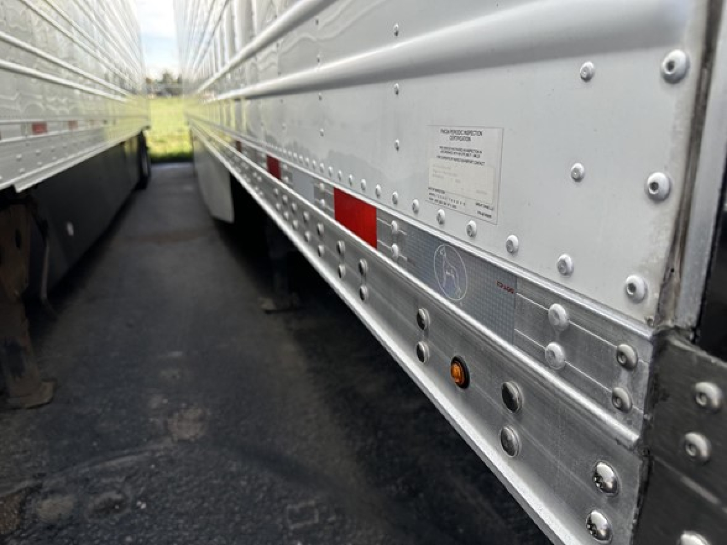 Side view of a Great Dane air ride reefer trailer showing riveted aluminum side panels, reflective tape, Gladhand area and identification sticker.