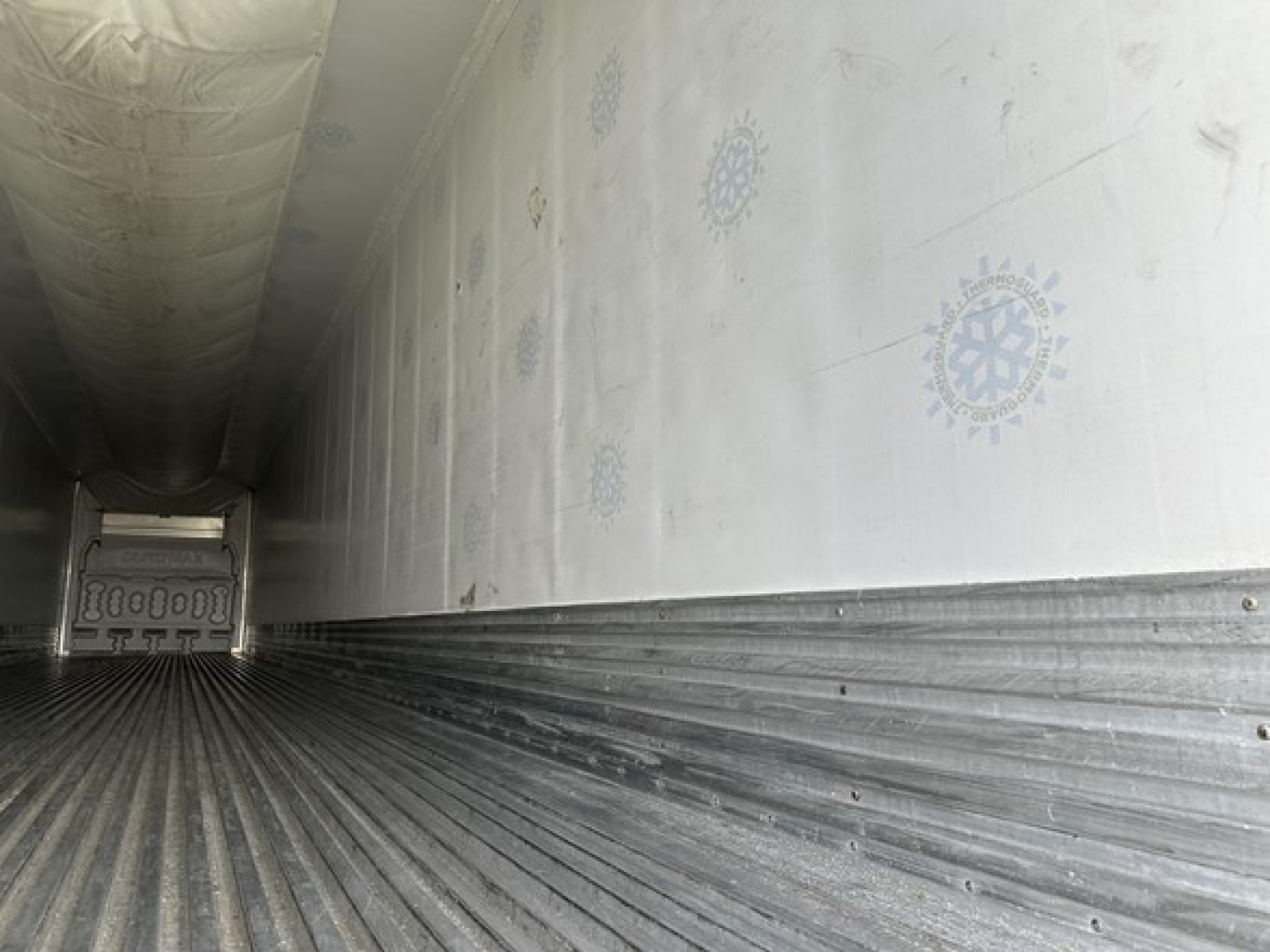 Inside of a Great Dane air ride reefer trailer cargo area showing ribbed floor and side walls with circular blue patterns and doors at far end.