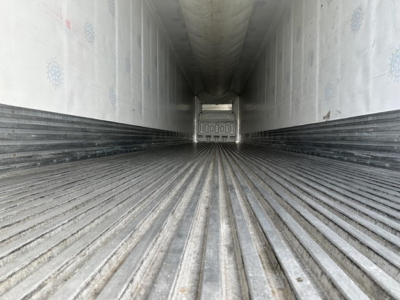 Trailer interior showing long refrigerated cargo area with ribbed floor and insulated walls, end of trailer visible