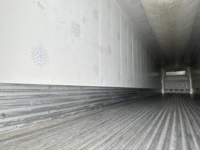Interior of trailer cargo area showing ribbed floor and side walls with ceiling insulation.