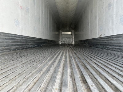 Trailer interior showing ribbed metal floor and insulated walls, rear door with latch visible at far end.