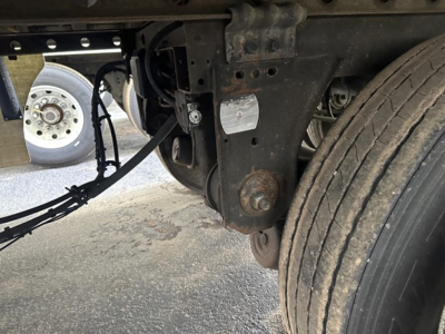Reefer trailer undercarriage showing wheel, suspension, and frame with a small label on the axle and some wiring.