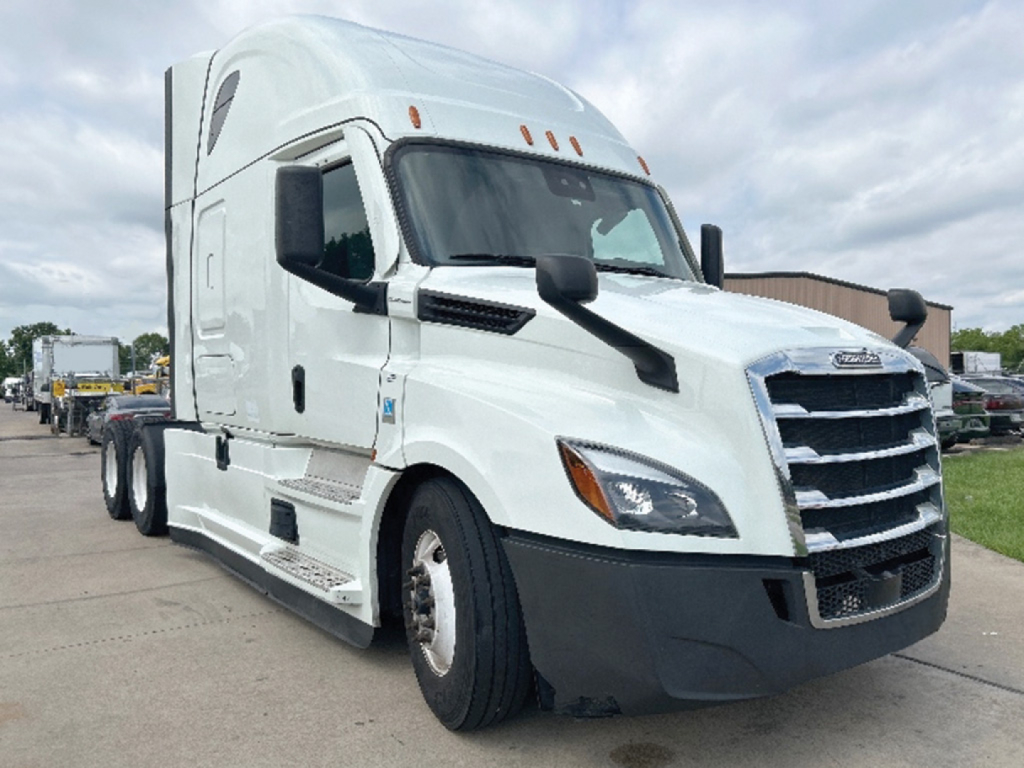 Truck cab of a 2021 Freightliner Cascadia126 with white exterior, showing front grille and headlights. Visible text: Freightliner logo on grille, side view mirrors, no other legible labels.