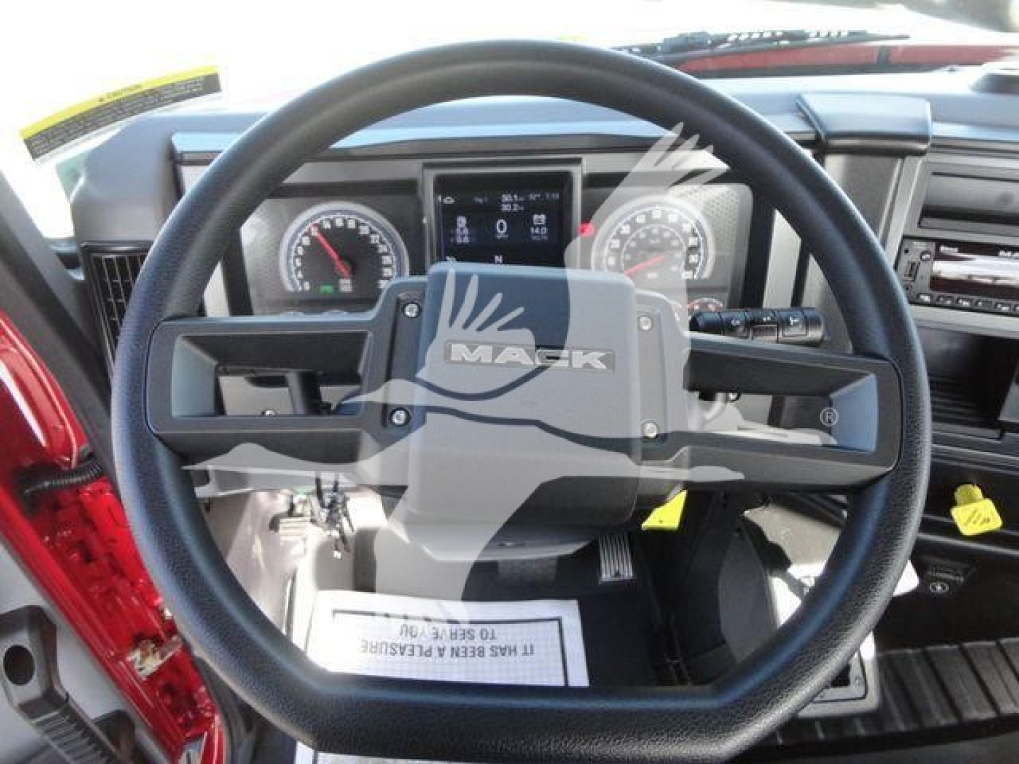 Mack MD6 truck cockpit showing steering wheel and dashboard gauges, central display, and control stalks.