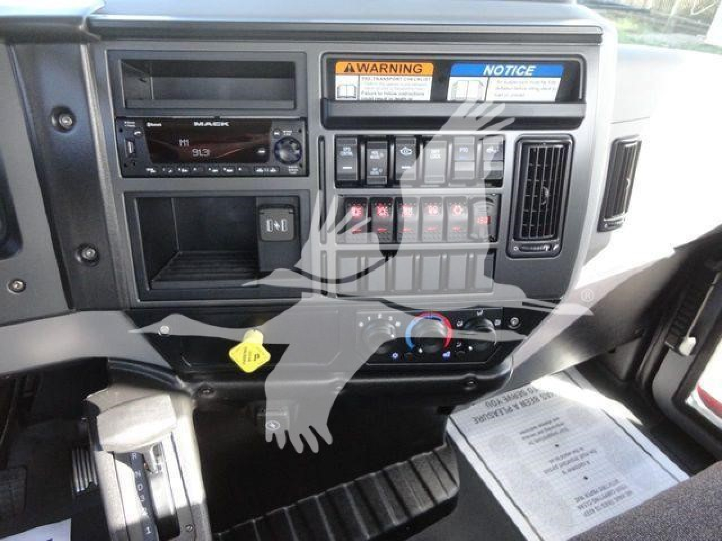 Dashboard of a 2027 Mack MD6 rollback truck showing instrument panel, warning labels, controls, and radio unit